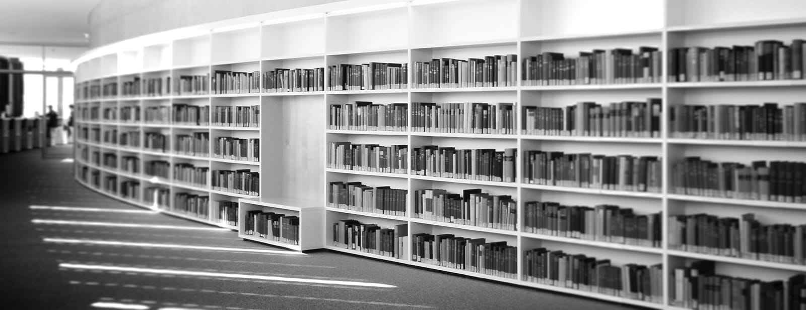 Grayscale photo of a curved hallway in a library